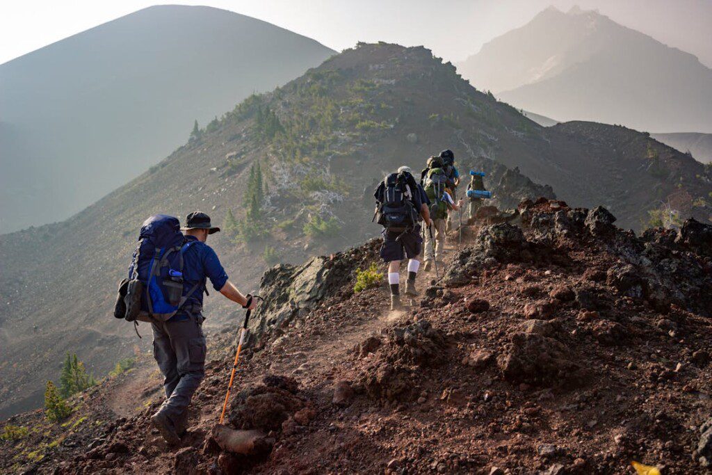A group of hikers with backpacks trekking along a rugged trail near Cherokee Lake, Tennessee, surrounded by scenic mountain views and natural beauty.