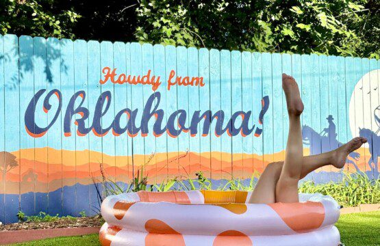 Howdy from Oklahoma mural at The Cowboy Retreat vacation rental in Oklahoma City — backyard view with inflatable pool and Western-style fence art