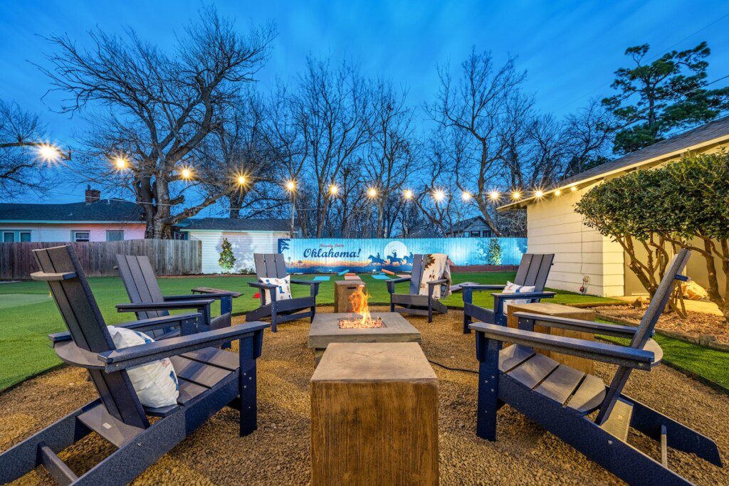 Family-friendly Oklahoma City vacation rental backyard with firepit, Adirondack chairs, string lights and a mini-golf green at The Cowboy Retreat.