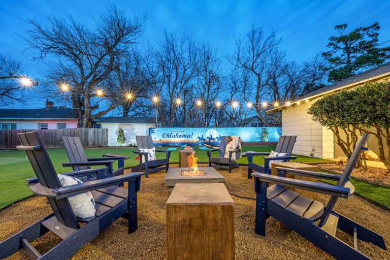 Family-friendly Oklahoma City vacation rental backyard with firepit, Adirondack chairs, string lights and a mini-golf green at The Cowboy Retreat.