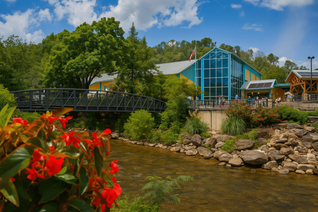 River view of a modern aquarium building with a pedestrian bridge and lush greenery in Gatlinburg Tennessee