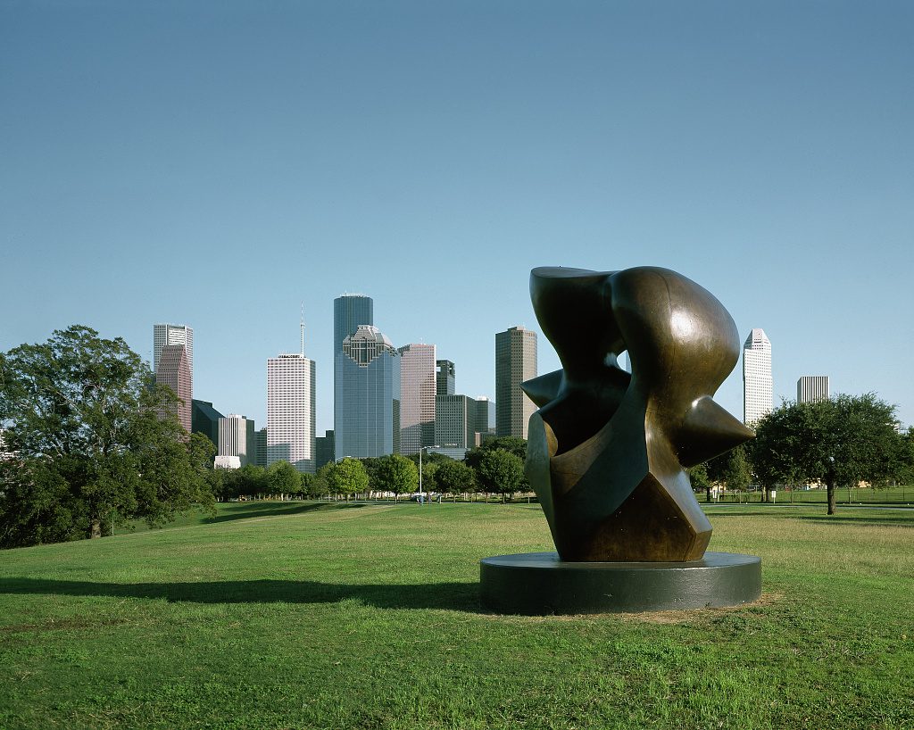 Buffalo Bayou Park Houston skyline with public art sculpture in foreground, green lawns and trees