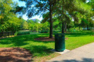 Discovery Green urban park in downtown Houston featuring lush green lawns, tree-lined pathways, and trash receptacle