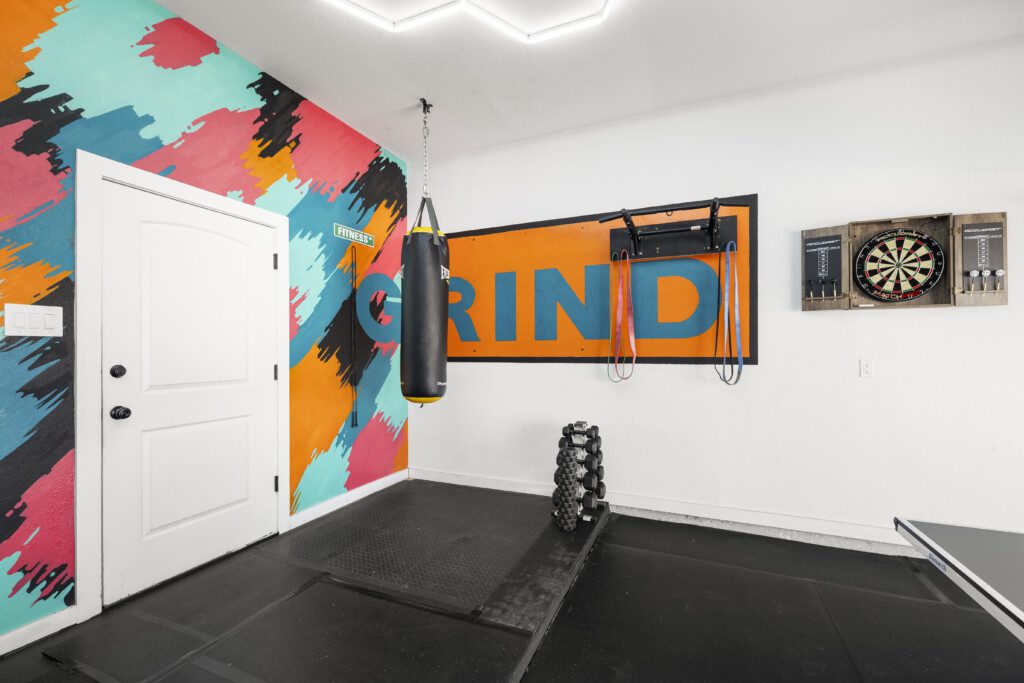 Garage fitness and game area with punching bag, dartboard, and GRIND sign at The Landing Pad Houston vacation rental near NRG Stadium
