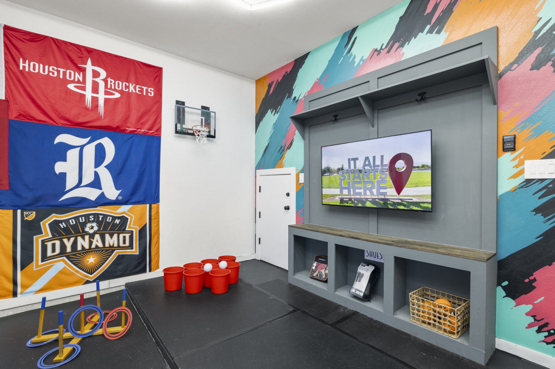 Garage game room with Houston sports flags, ring toss, and beer pong at The Landing Pad Houston vacation rental near NRG Stadium