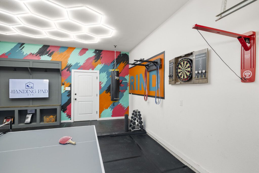 Garage game room with ping pong table, punching bag, and dartboard at The Landing Pad Houston vacation rental near NRG Stadium