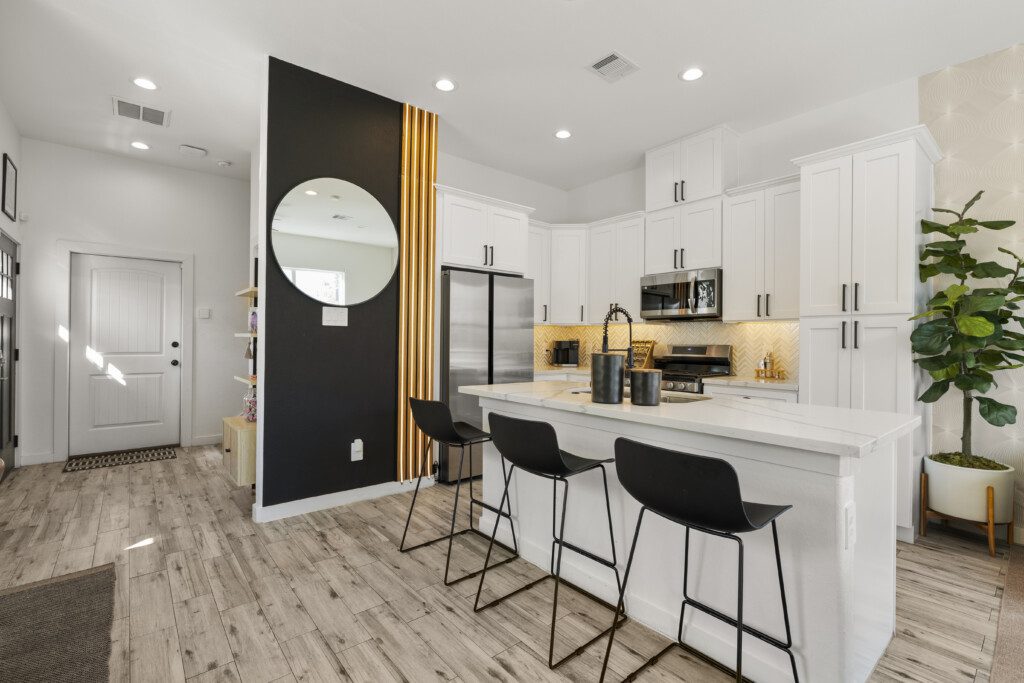 Kitchen with bar seating, black accent wall, and front door view at The Landing Pad Houston vacation rental near NRG Stadium