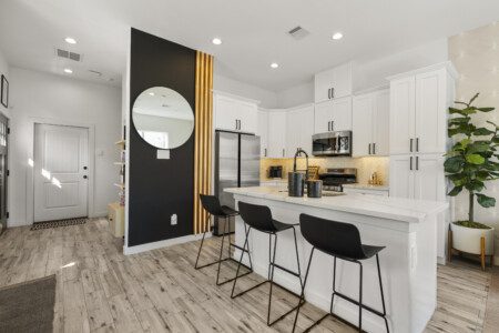 Kitchen with bar seating, black accent wall, and front door view at The Landing Pad Houston vacation rental near NRG Stadium