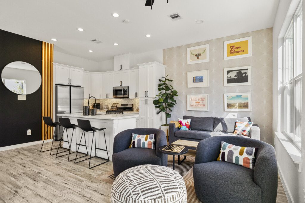 Open concept living room and kitchen at The Landing Pad Houston vacation rental with navy sofas and gallery wall near NRG Stadium
