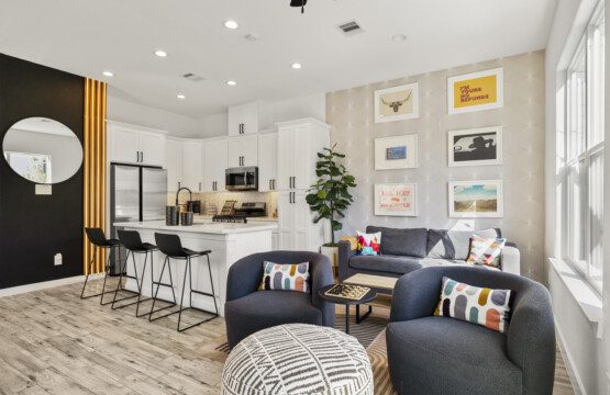 Open concept living room and kitchen at The Landing Pad Houston vacation rental with navy sofas and gallery wall near NRG Stadium