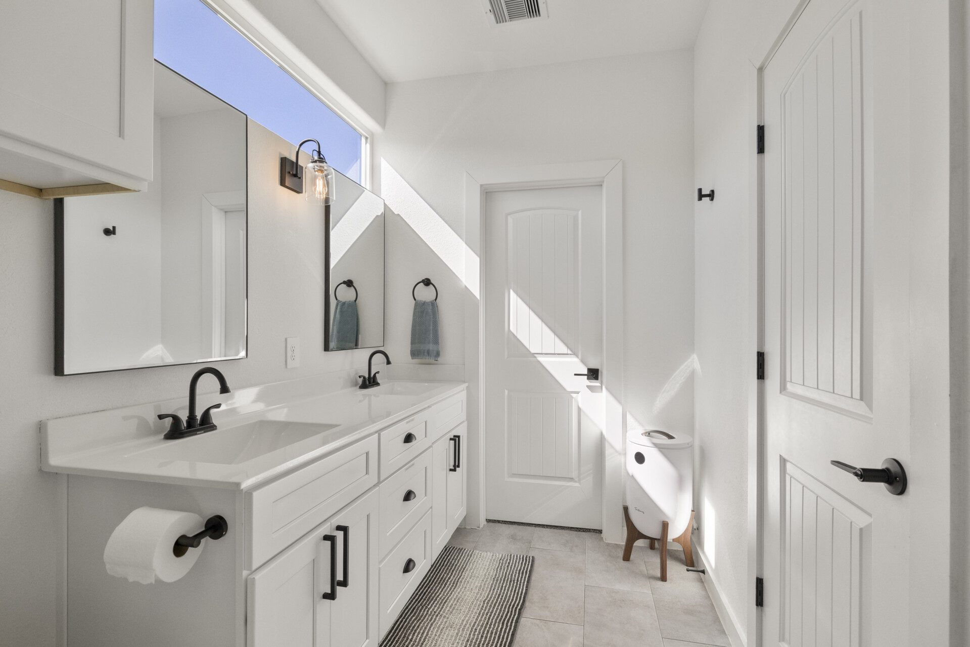 Clean white Jack-and-Jill bathroom at The Landing Pad Houston vacation rental with double vanity, bright natural light near NRG Stadium