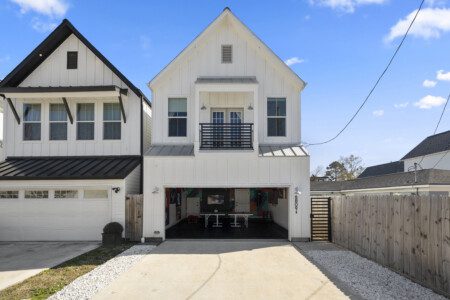 Front exterior of modern white Houston vacation rental with open garage and private driveway